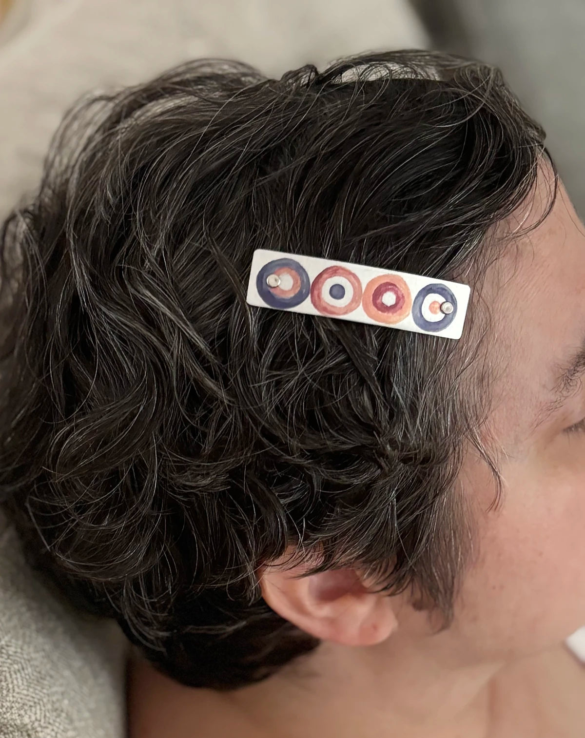 XS petite metal boutique hair clip featuring a modern neutral circles design, handmade by Robbin V. Davis Studio in North Carolina. Shown in short, curly dark gray hair.