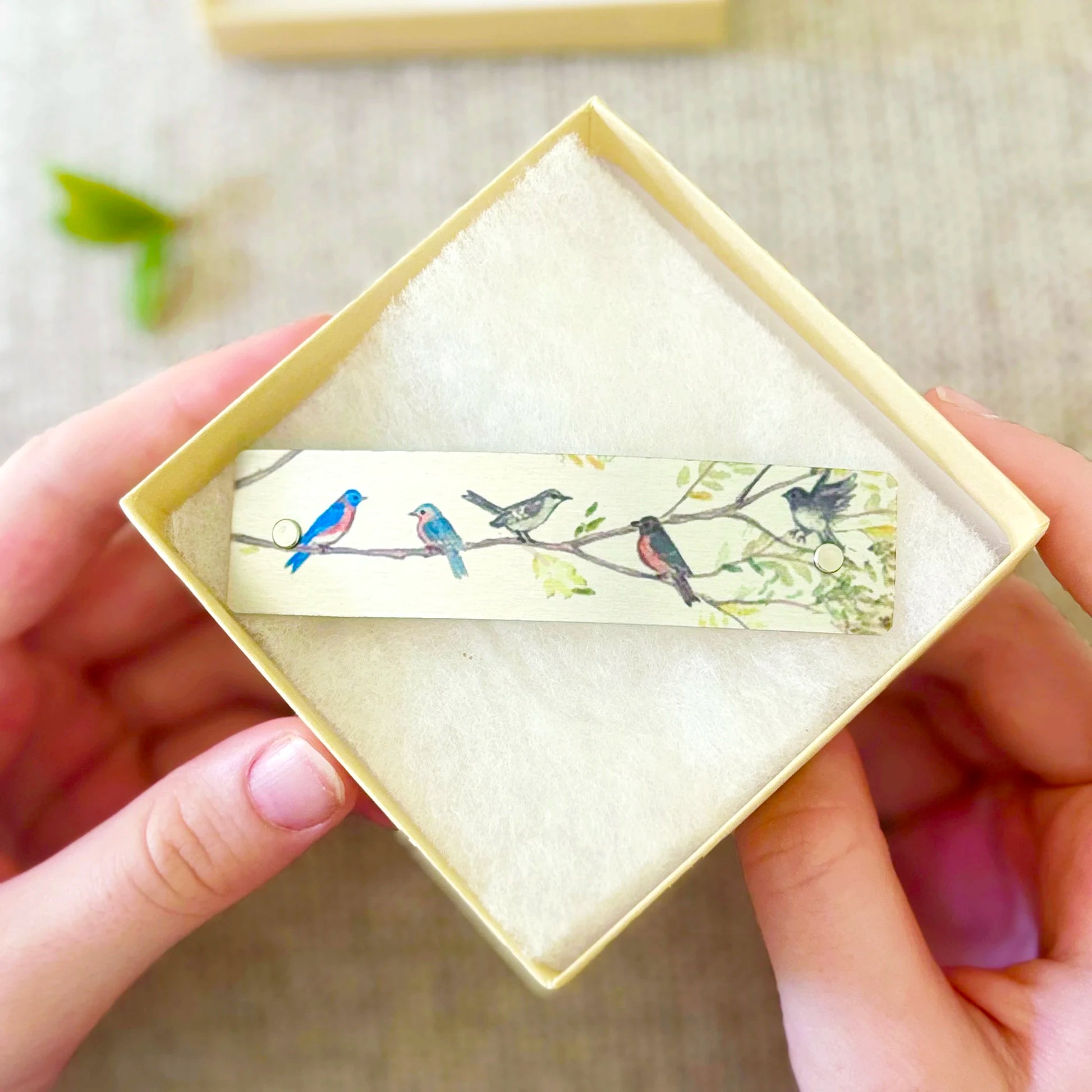 A close up of an open gift box with a Birds on Branches French barrette hair clip inside.