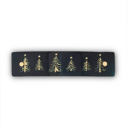 A black rectangular hair clip featuring five whimsical gold Christmas tree designs with stars, shown against a plain white background.