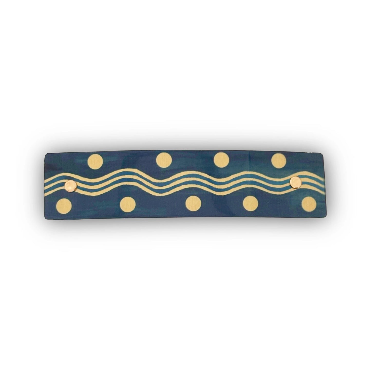 A rectangular hair barrette with a gold wavy line and polka dot pattern, shown against a plain white background.