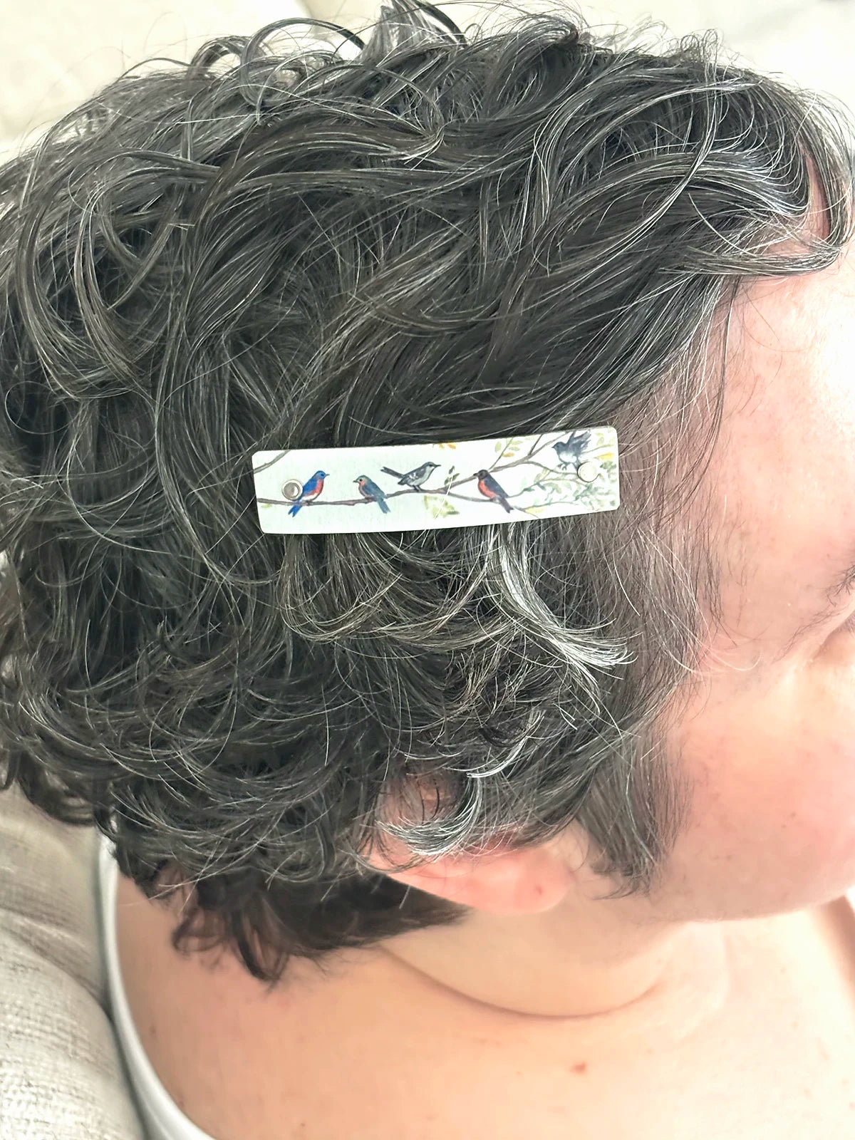 A close up of short, curly gray hair wearing a Birds on Branches extra small French barrette hair clip.
