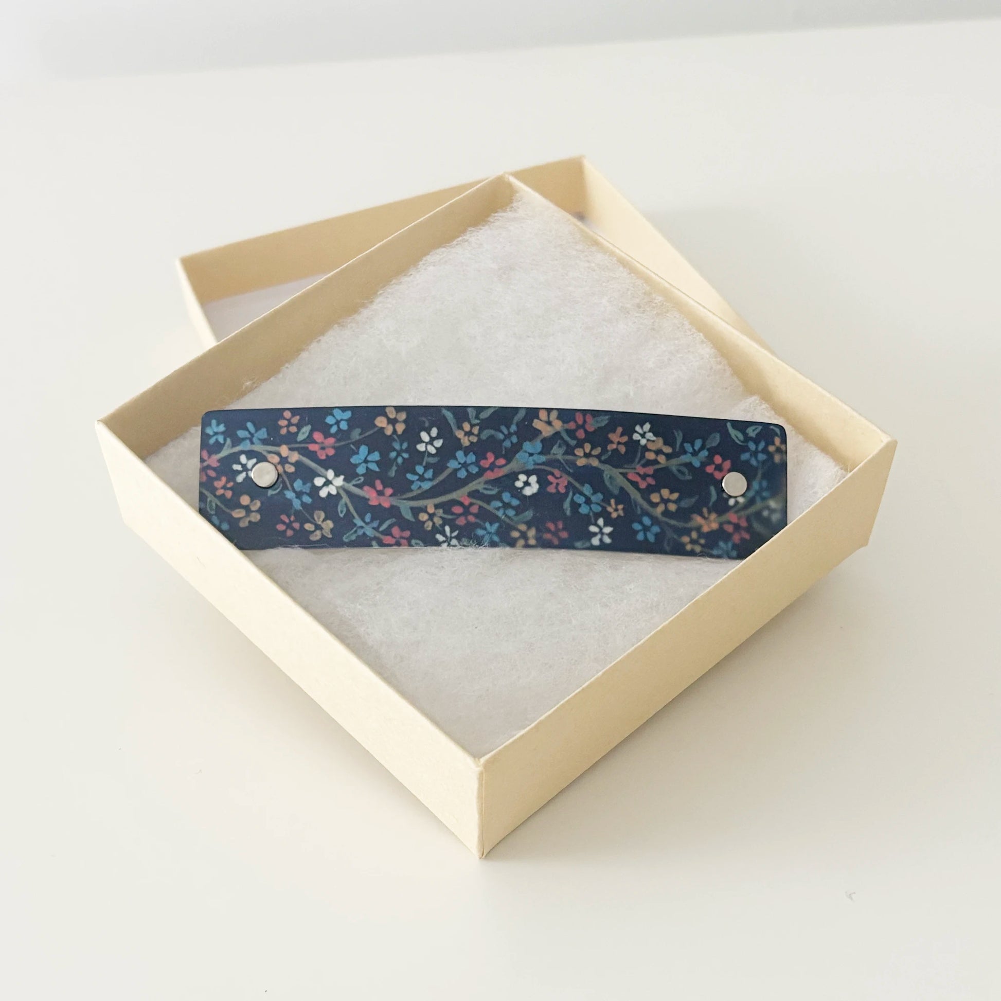 Navy floral hair clip, presented in a gift box.
