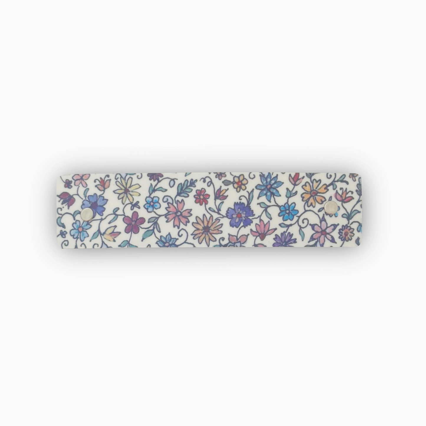 A boutique French barrette hair clip with an all-over floral pattern in blue, purple, pink, and yellow on a white background, shown against a plain white backdrop.