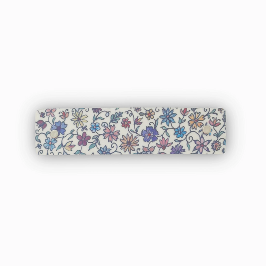 A boutique French barrette hair clip with an all-over floral pattern in blue, purple, pink, and yellow on a white background, shown against a plain white backdrop.