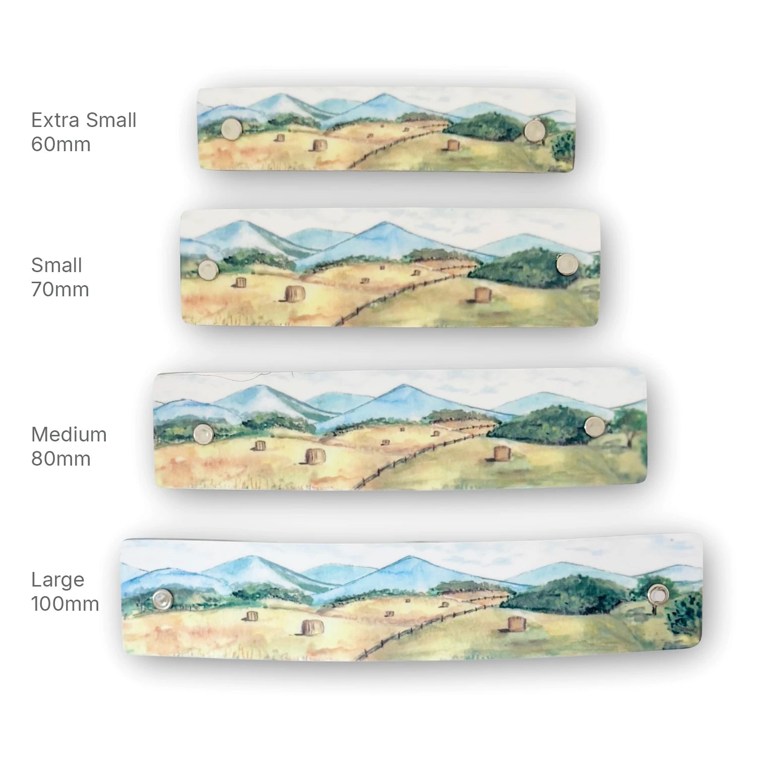 Four rectan boutique hair clips shown in different sizes (Extra Small 60mm, Small 70mm, Medium 80mm, Large 100mm) lined up vertically on a white background. Each barrette features a watercolor landscape of a green valley with hayriolls and blue mountains.