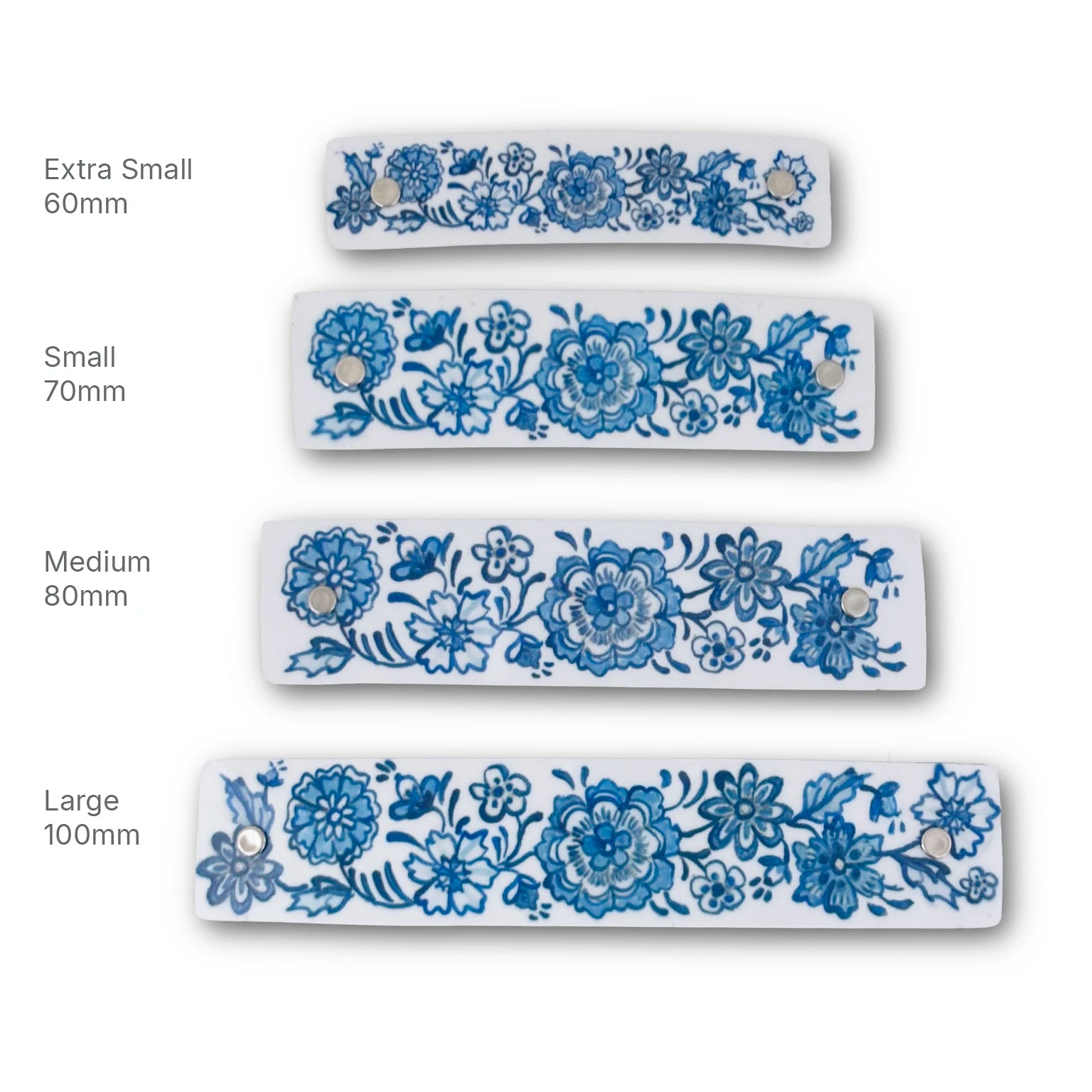 Four  white barrettes with blue floral Delft patterns shown in four sizes: Extra Small 60mm, Small 70mm, Medium 80mm, and Large 100mm, arranged vertically on a white background with size labels.