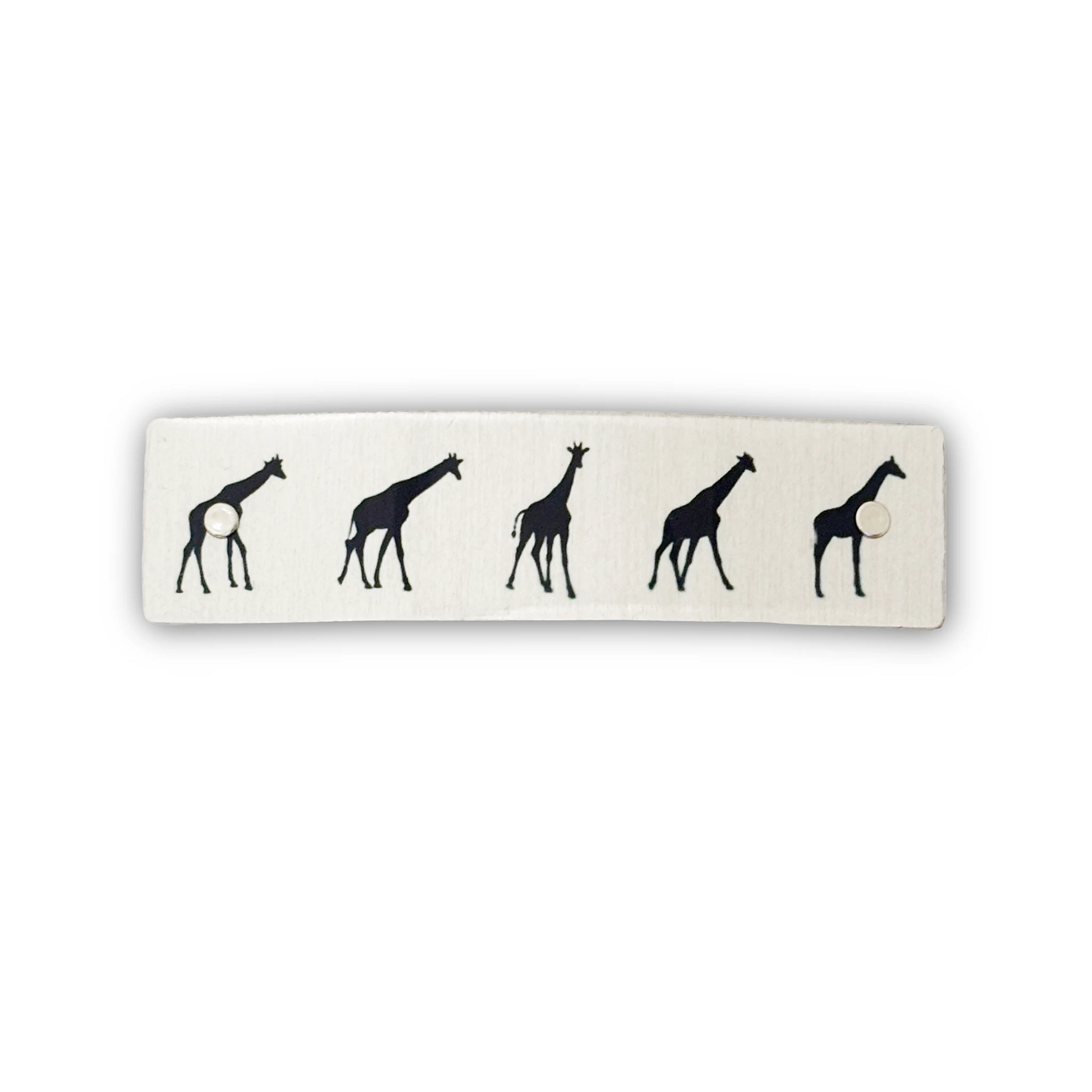 A rectangular silver hair clip, featuring a black silhouette pattern of five giraffes arranged in a row.