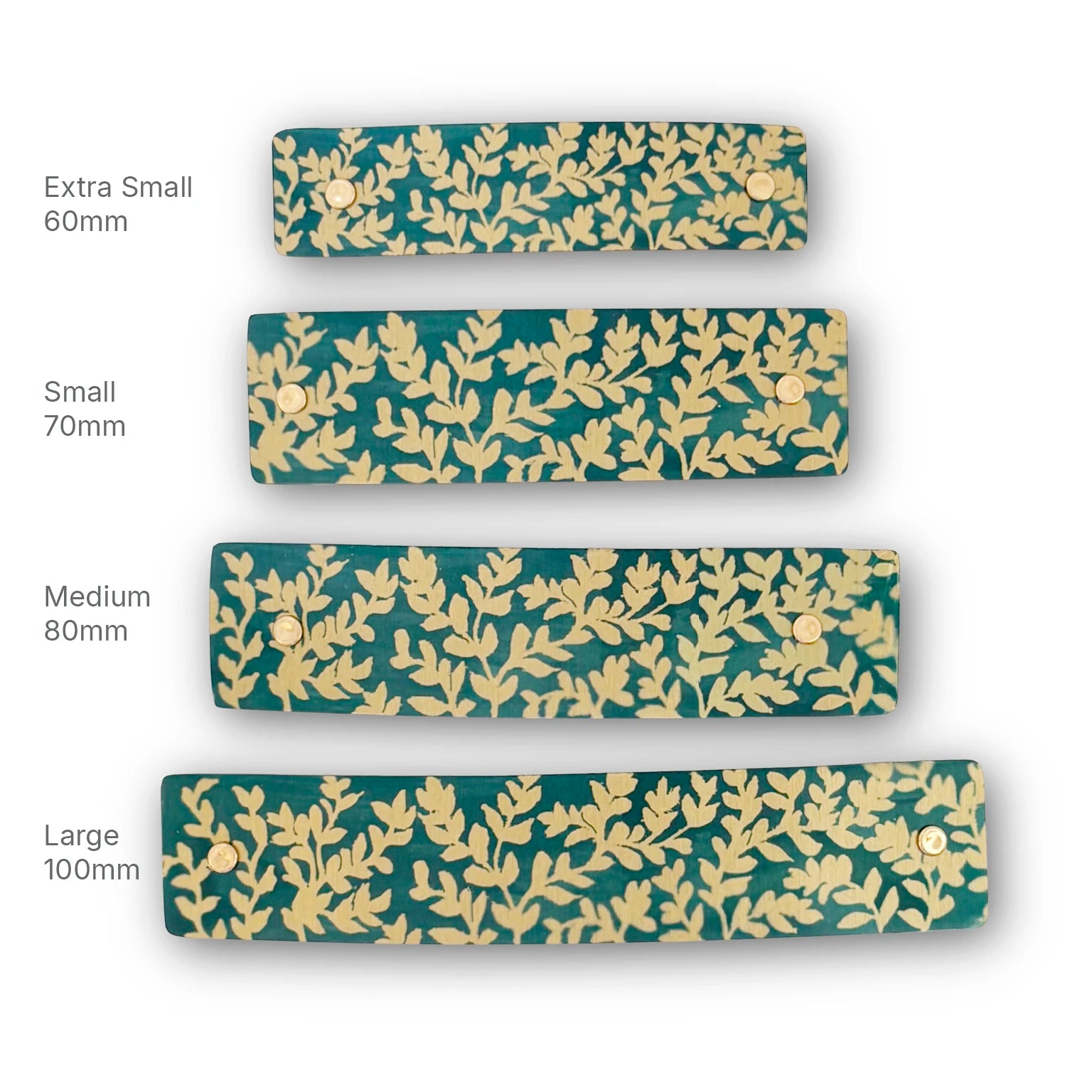 Four rectangular hair barrettes shown in different sizes labeled Extra Small 60mm, Small 70mm, Medium 80mm, and Large 100mm on a white background. The clips have a dark teal background with an artistic repeating gold leaf pattern.