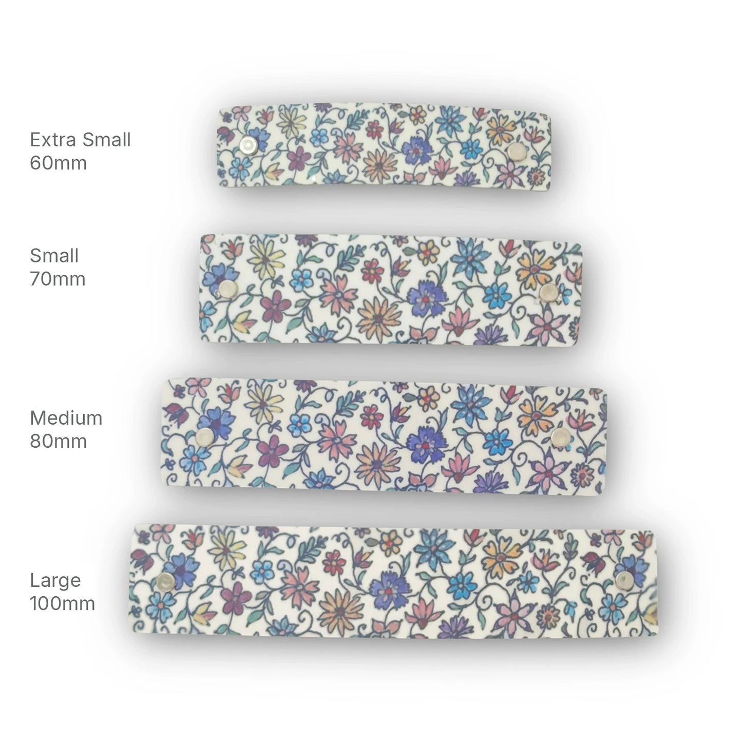 Four floral-patterned handmade metal hair clips shown in different sizes labeled Extra Small 60mm, Small 70mm, Medium 80mm, and Large 100mm on a white background.