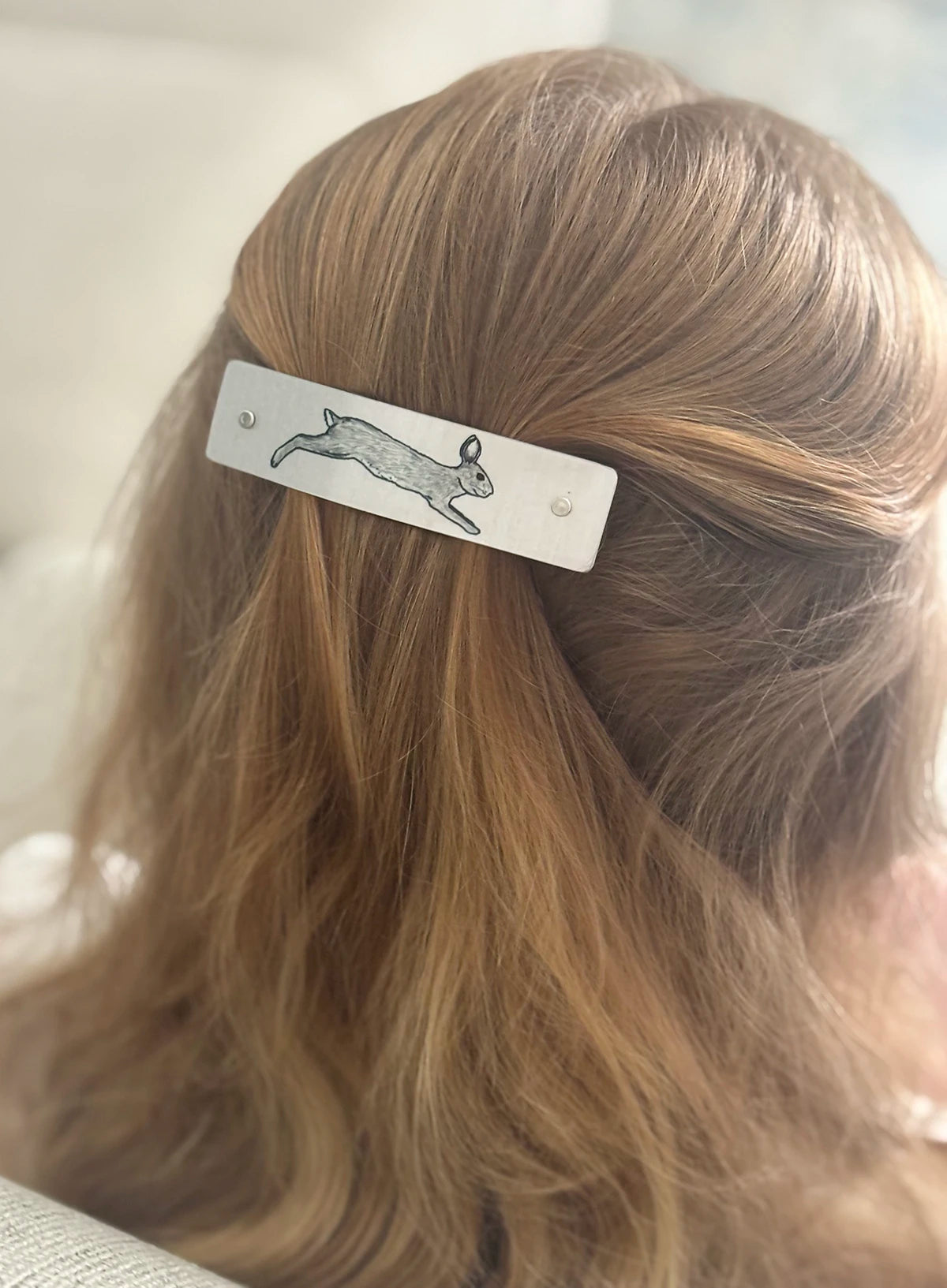A close-up lifestyle shot of a person's hair wearing a silver metal hair clip with an original rabbit design.