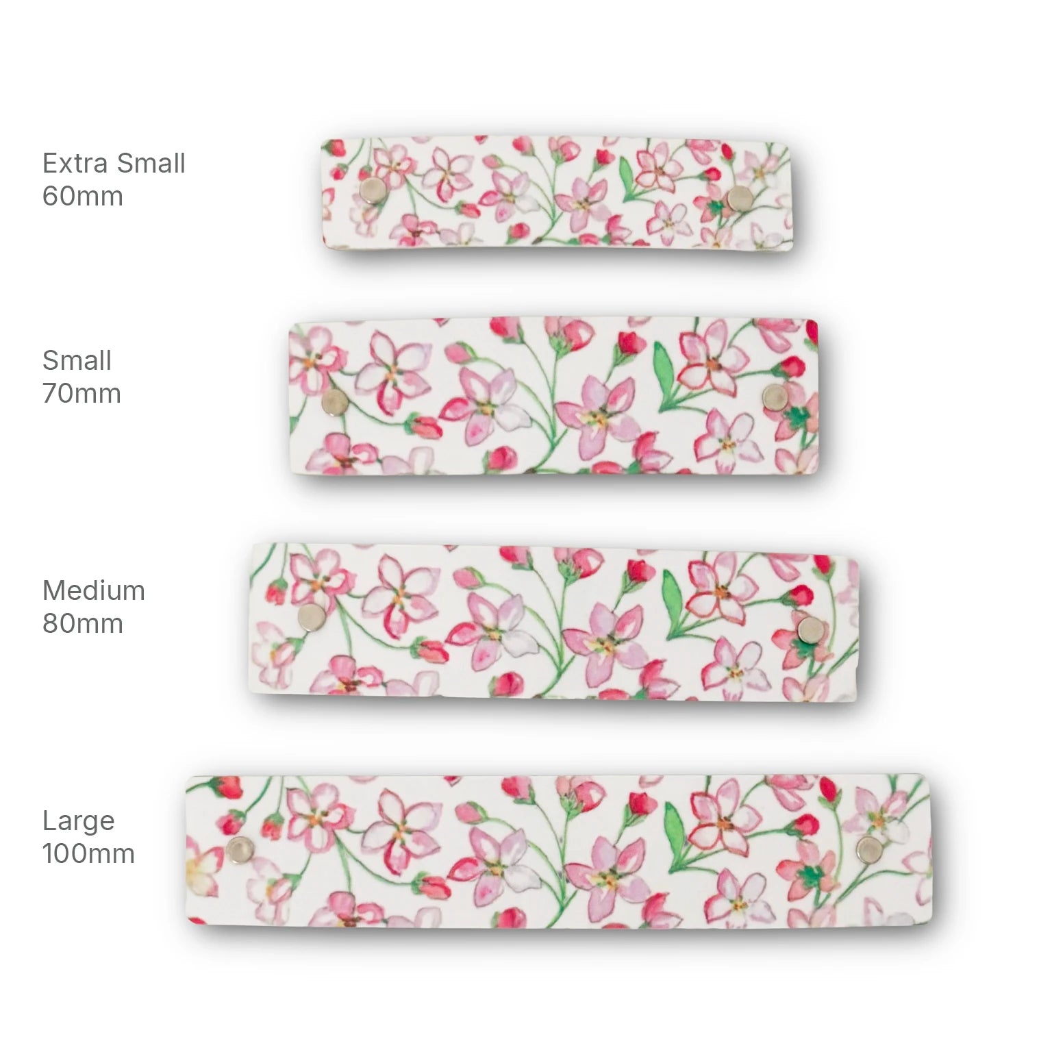 Four French barrettes with a pink and green floral pattern on a white background, shown in sizes Extra Small 60mm, Small 70mm, Medium 80mm, and Large 100mm, arranged vertically with size labels on a white background.