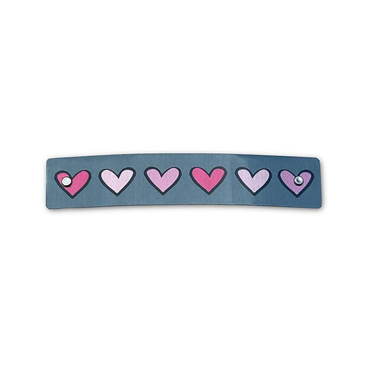 A curved rectangular hair clip in a slate color, decorated with a row of hearts in shades of pink.