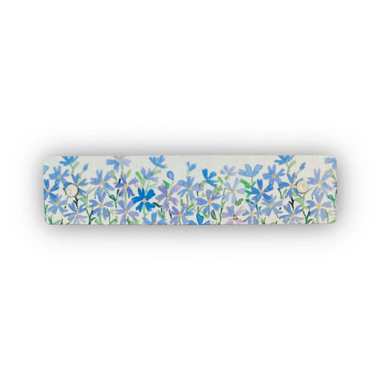 A rectangular silver hair clip featuring a dense watercolor-style floral pattern of blue and purple flowers with green stems, shown against a plain white background.