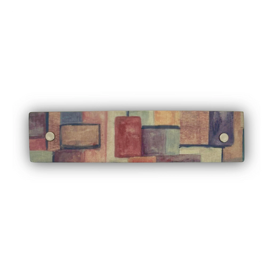 A rectangular hair clip featuring an abstract shaded geometric pattern of overlapping blocks in muted earthy tones,  shown against a plain white background.