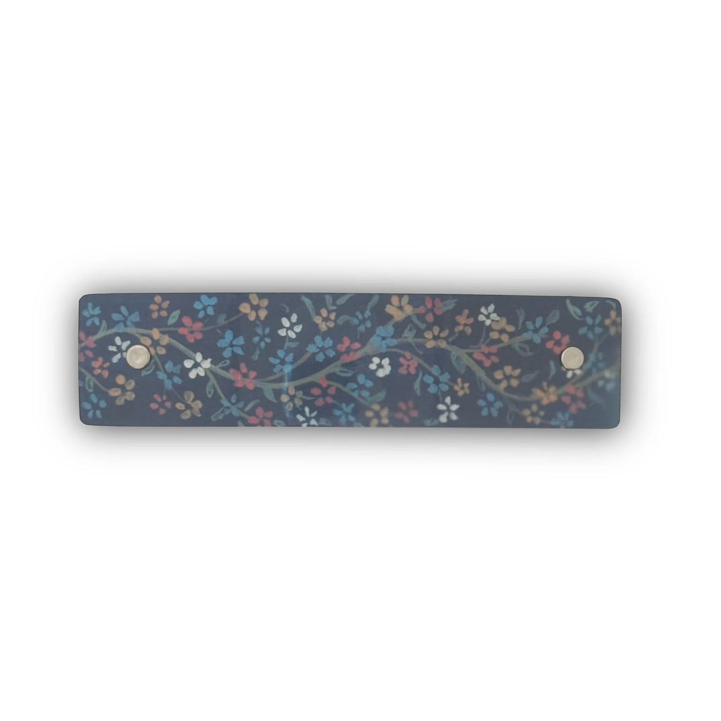 A rectangular boutique hair clipwith a dark navy blue background and a delicate floral vine pattern in muted red, blue, yellow, and white. Features original artwork by Robbin V. Davis.