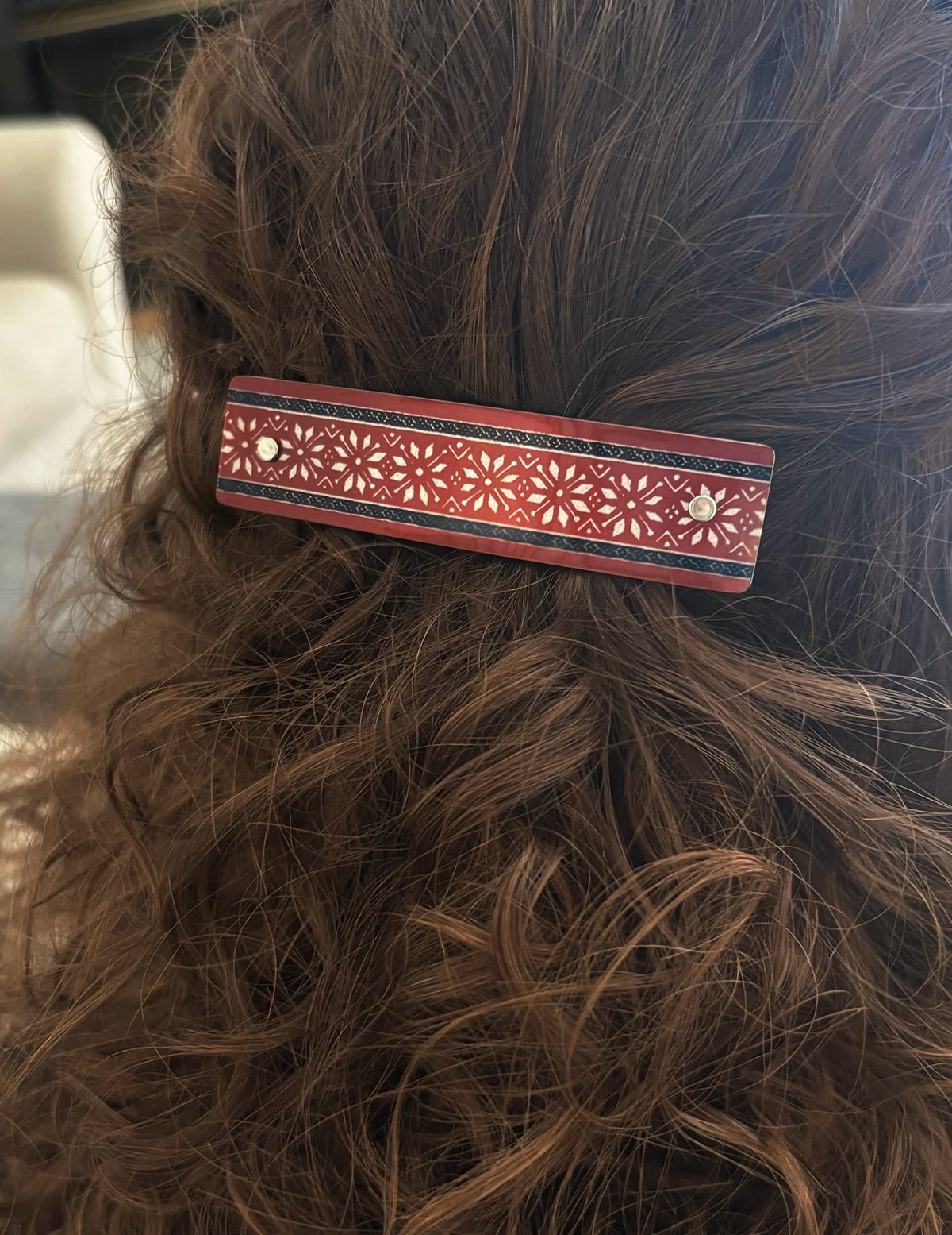 Scandinavian pattern hair clip in curly brown hair.