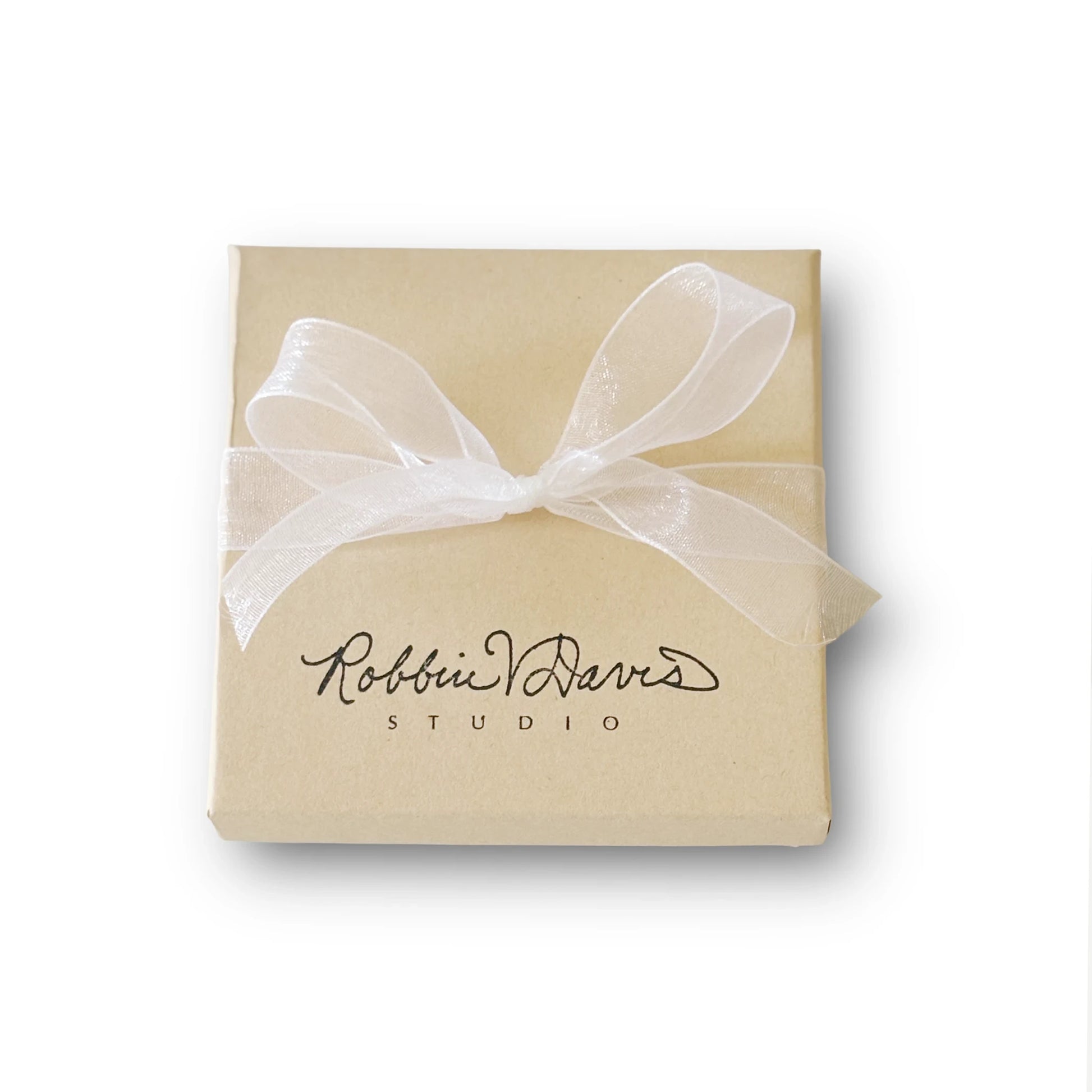A square kraft paper gift box tied with a sheer white ribbon bow, featuring the black printed logo 'Robbin V.  Davis STUDIO' on the front, set against a plain white background.