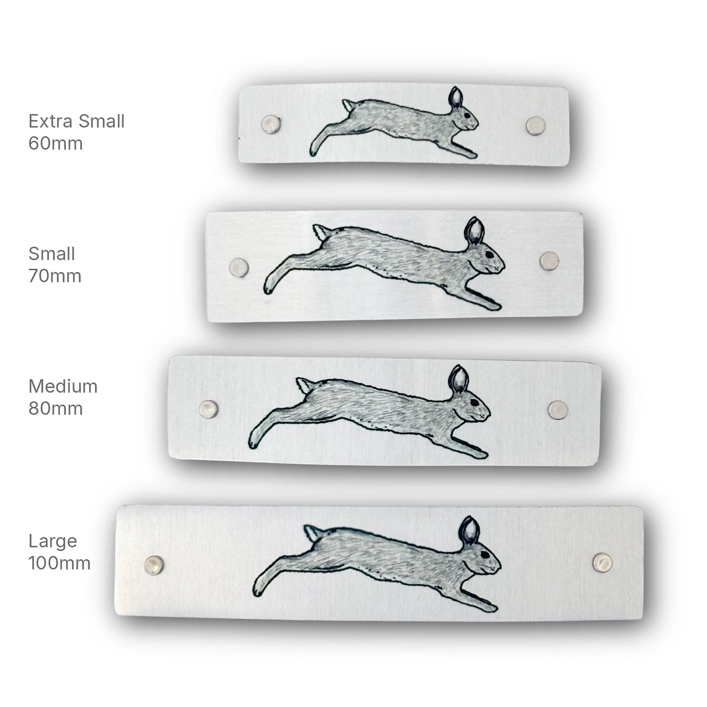 Four rectangular brushed-metal barrettes shown in different sizes labeled Extra Small 60mm, Small 70mm, Medium 80mm, and Large 100mm, decorated with original artwork of a leaping rabbit.