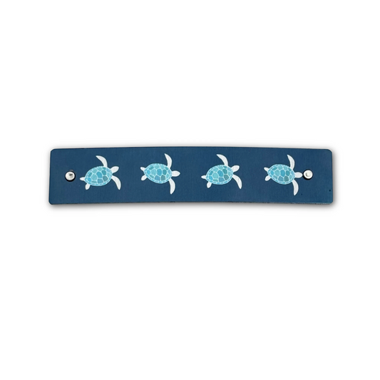 Handmade boutique hair clip featuring blue and silver sea turtles on a navy blue background.
