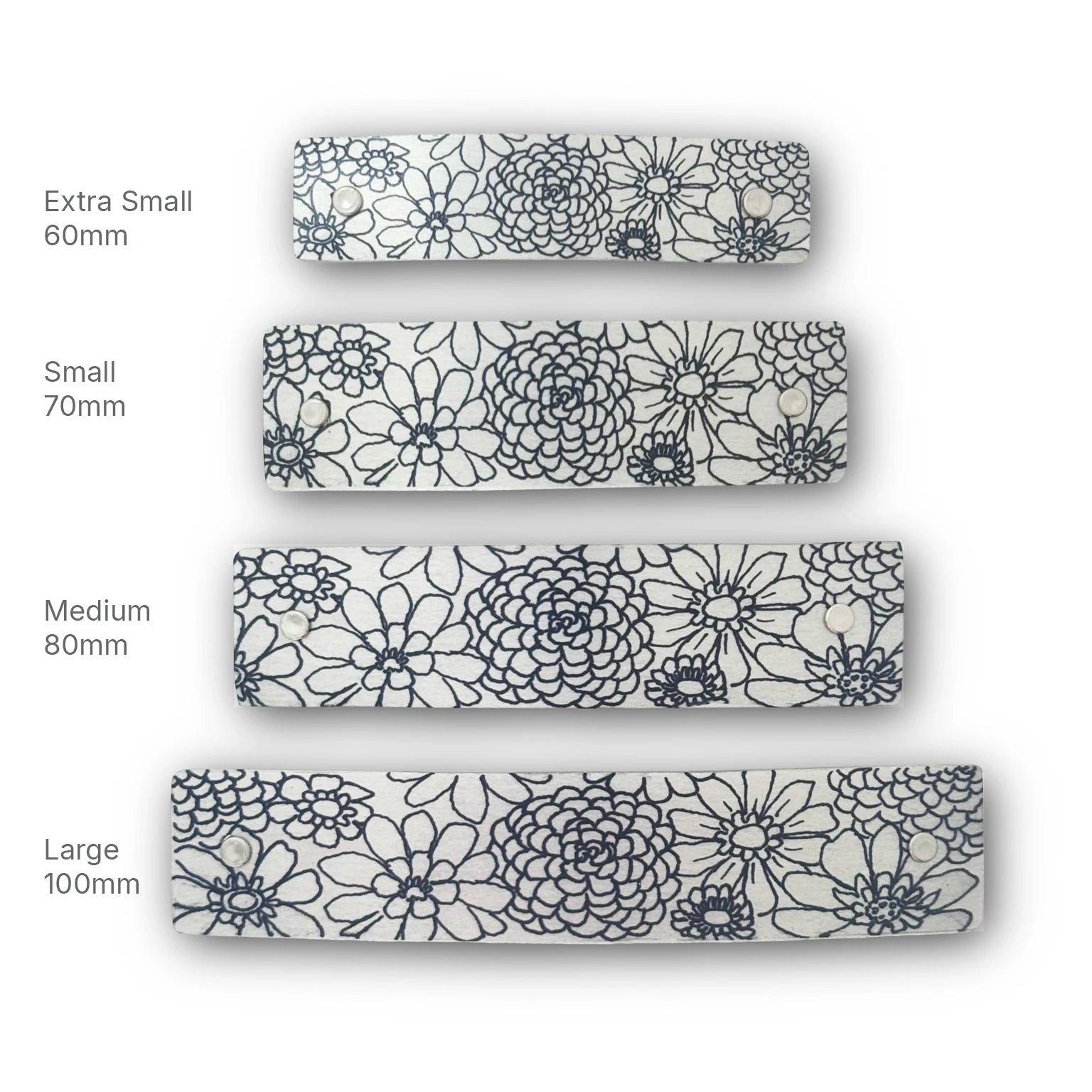 Four French barrettes shown in different sizes labeled Extra Small 60mm, Small 70mm, Medium 80mm, and Large 100mm, all featuring a black zinnia floral line-art pattern on a silver background.