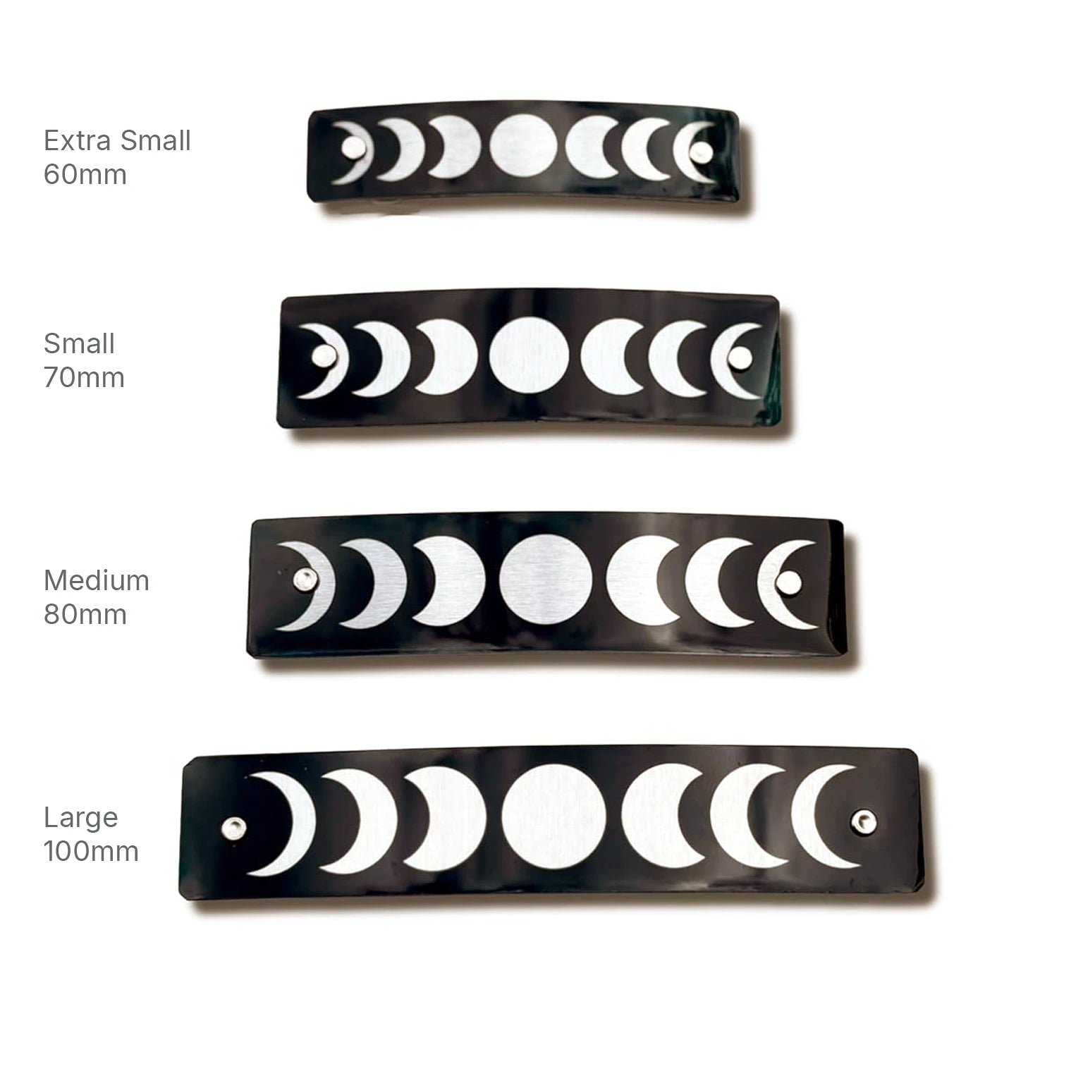 Four black rectangular barrettes with white moon phase graphics, shown in four sizes labeled Extra Small 60mm, Small 70mm, Medium 80mm, and Large 100mm on a white background.