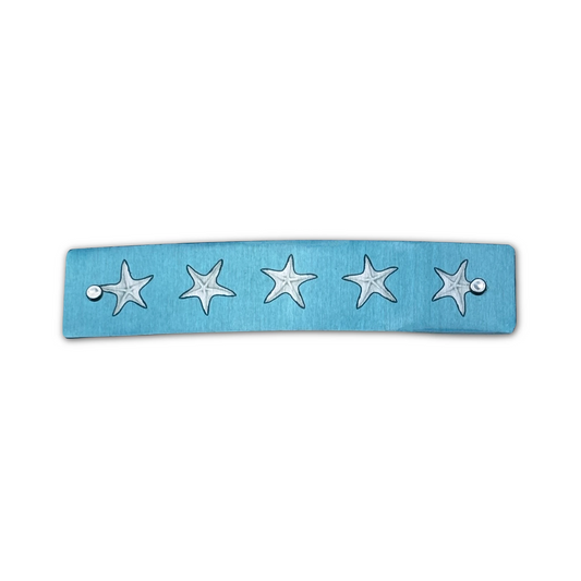 A light blue rectangular barrette featuring five  silver starfish motifs, shown against a plain white background.